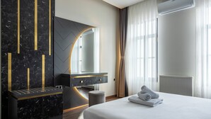 A modern hotel room with a large bed, a vanity with a mirror, and a marble wall with gold accents. - Nm Suites Beyoglu (Istanbul)