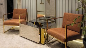 A modern interior with two leather armchairs, a glass-top table, and a large decorative letter 'N' on the wall. - Nm Suites Beyoglu (Istanbul)