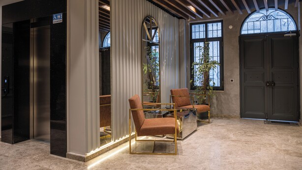 A lobby with a reception desk, two brown leather chairs, a glass table, a large window, and a door. - Nm Suites Beyoglu (Istanbul)