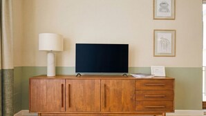 A wooden TV stand with a flat-screen TV, a lamp, and framed pictures on the wall. - CS Trastevere Glorioso Signature Apt. (Rome)