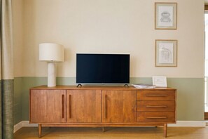 A wooden TV stand with a flat-screen TV, a lamp, and framed pictures on the wall. - CS Trastevere Glorioso Signature Apt. (Rome)