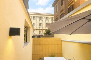 A narrow alleyway with a wooden fence, a white table, and a building with classical architecture in the background. - CS Trastevere Glorioso Signature Apt. (Rome)