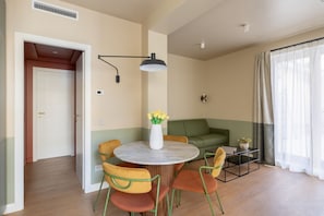 A modern living room with a round table, green and yellow chairs, a green sofa, and a window with sheer curtains. - CS Trastevere Glorioso Signature Apt. (Rome)