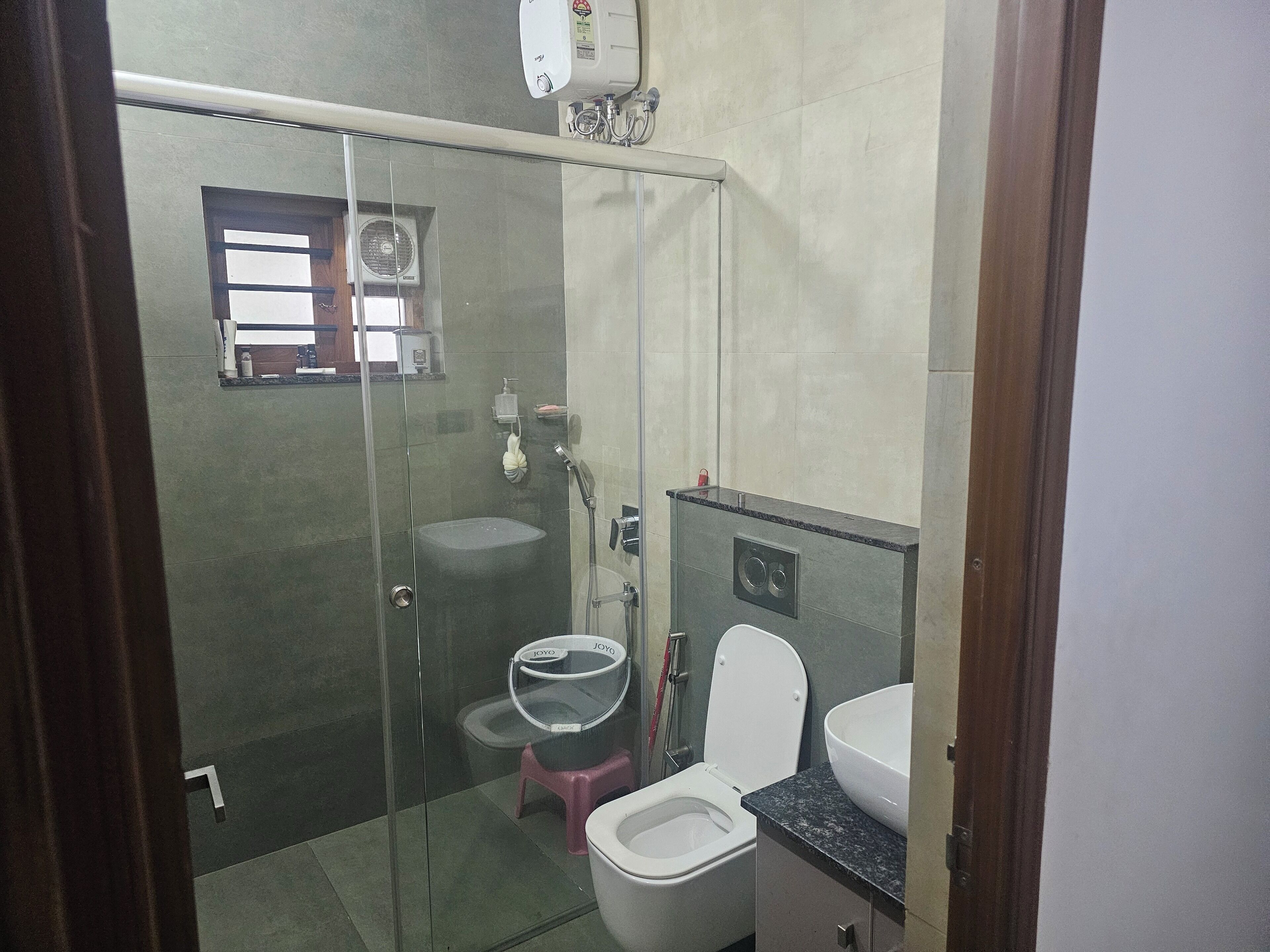 Casa de banho com cabine de duche em vidro, sanita e lavatório.