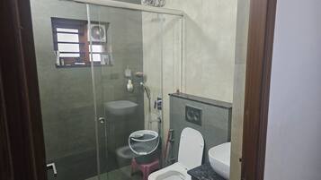 Casa de banho com cabine de duche em vidro, sanita e lavatório.