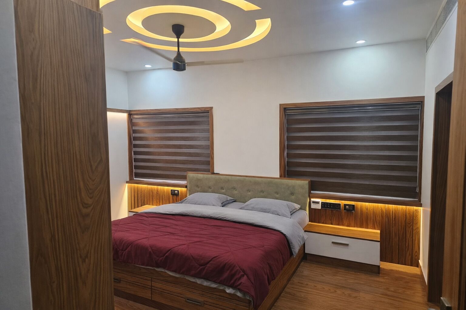 Ein Schlafzimmer mit Bett, Holz-Kopfteil und integrierter Beleuchtung.