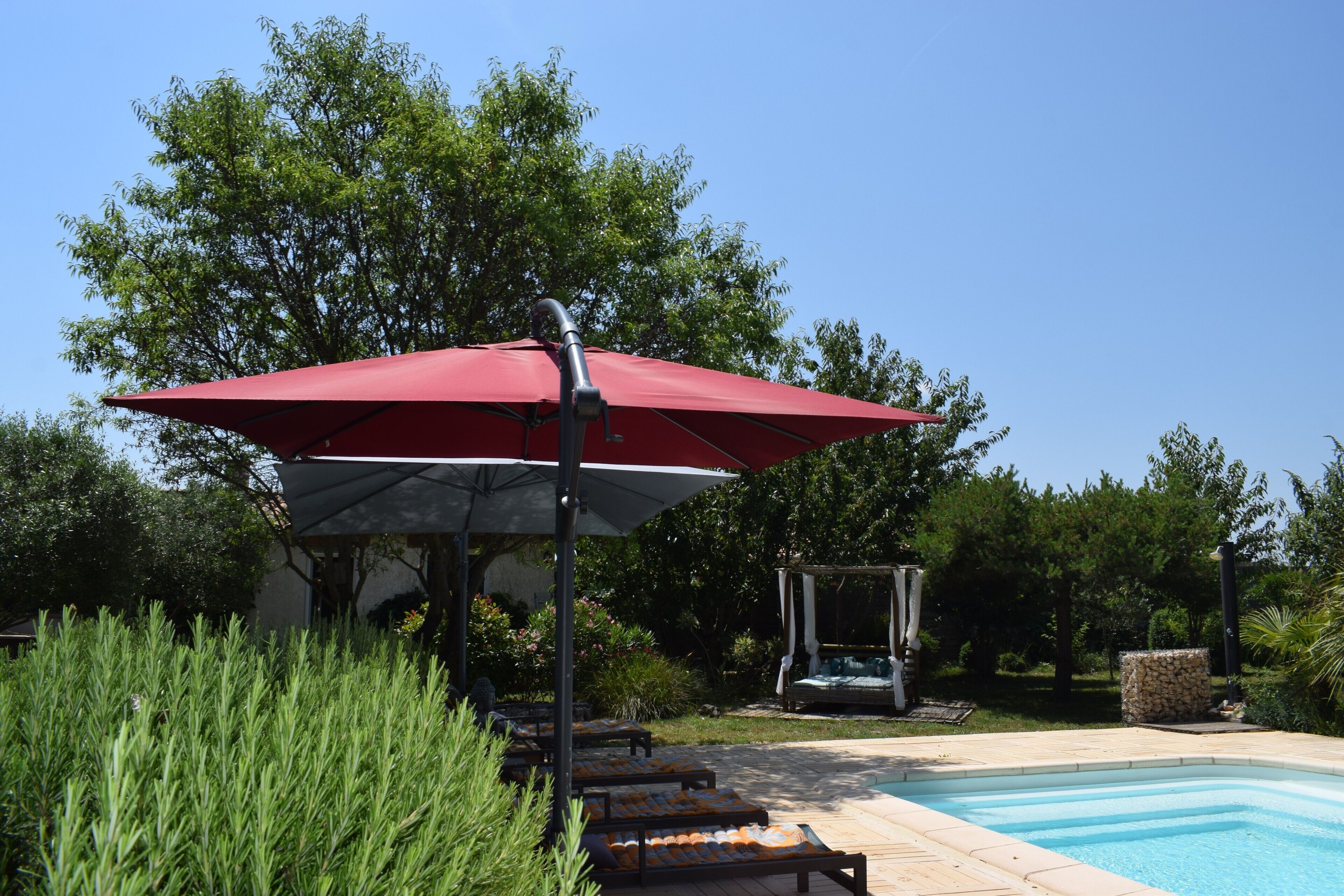 A pool area with lounge chairs and a red umbrella.