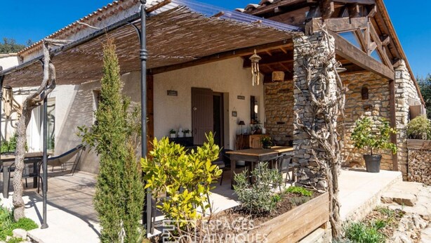 A rustic stone house with a wooden porch, a dining area, and a stone fireplace.
