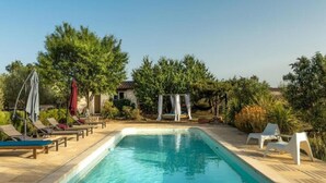 A rectangular swimming pool with lounge chairs and a swing set in a landscaped outdoor area.