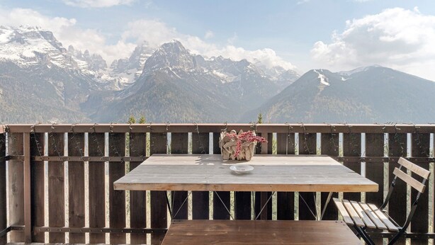 A wooden table with a vase of flowers, a plate, and a bench, overlooking a mountainous landscape. - Apartment 'Relax At The Mountain' with Mountain View, Shared Terrace and Wi-Fi (Madonna di Campiglio)