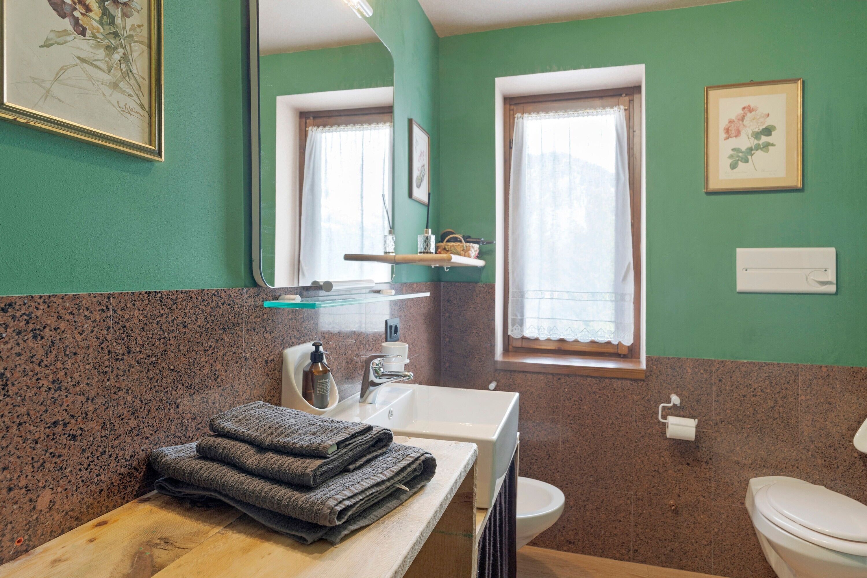 Un baño con lavabo, espejo, inodoro y ventana.