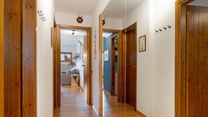 A wooden hallway with a door on the right, a mirror, and a number on the wall. - Apartment 'Relax At The Mountain' with Mountain View, Shared Terrace and Wi-Fi (Madonna di Campiglio)