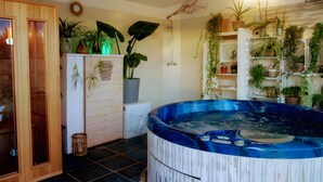 A spa room with a hot tub, wooden cabinets, and various potted plants.