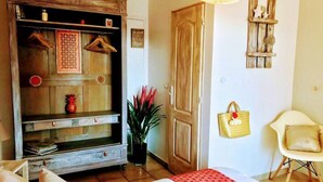 A bedroom with a bed, a wardrobe, a chair, and a wall-mounted shelf.