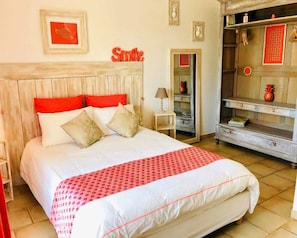 Une chambre d’hôtel avec un lit, une table de chevet, une armoire et un mur orné d’un panneau indiquant « Souriez ».