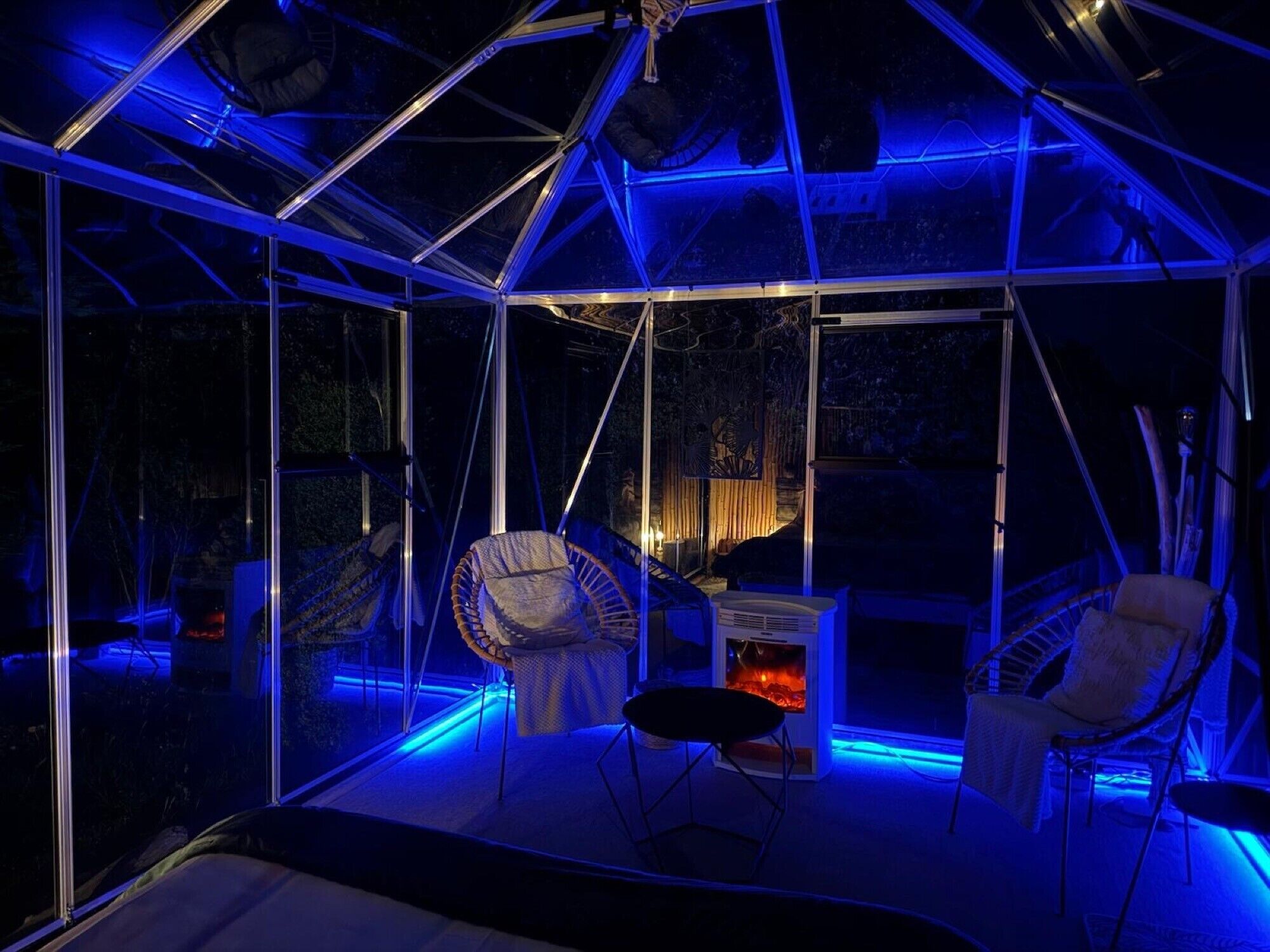 Une structure en forme de dôme géodésique dotée d’un foyer, de sièges et de murs en verre.
