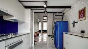A modern kitchen with white cabinets, a blue refrigerator, and a stainless steel stove. - RentPlanet - Apartament Lelewela (Wrocław)