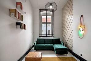 Un salon moderne comprenant un canapé d’angle, des étagères, une table en bois et un luminaire mural original.
