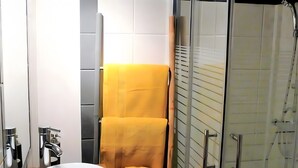 Ein modernes Badezimmer mit einer Glasdusche, einem weißen Waschbecken und einem gelben Handtuch.