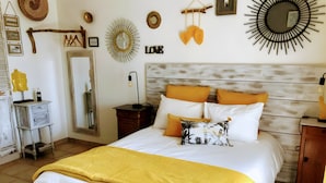 Ein Bett mit weißer und gelber Bettwäsche, ein Holz-Kopfteil und ein Spiegel darüber.