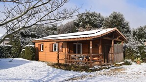 Une cabane en bois avec une véranda, une table à manger et un banc.