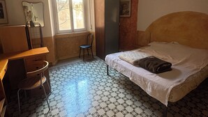 Un dormitorio con cama, escritorio, silla, lámpara colgante y ventana.