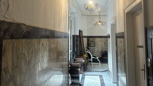 Un pasillo con piso de mármol, una lámpara de araña y una escalera que lleva a otra habitación.