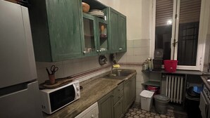 Una cocina compacta con armarios verdes, un microondas, un lavavajillas y baldosas de suelo con diseño.