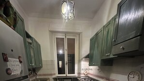 Una cocina funcional con piso de baldosas, un refrigerador, una estufa y armarios verdes.