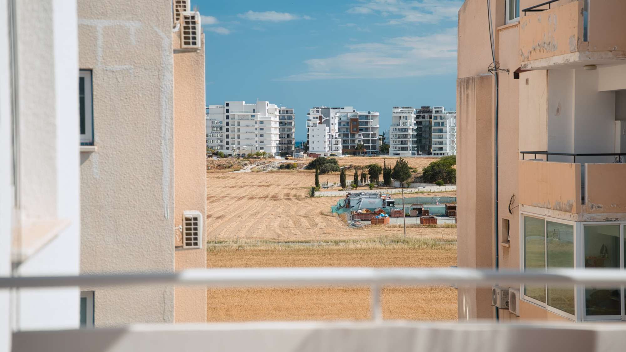 Una veduta di una zona residenziale con diversi condomini, una distesa sabbiosa e alcuni materiali edili in vista.