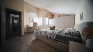 Ein Schlafzimmer mit einem Bett, einem Schreibtisch, einem Stuhl und einer Pendelleuchte.