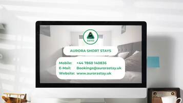 A computer monitor displaying information for Aurora Short Stays, including a mobile number, email, and website.