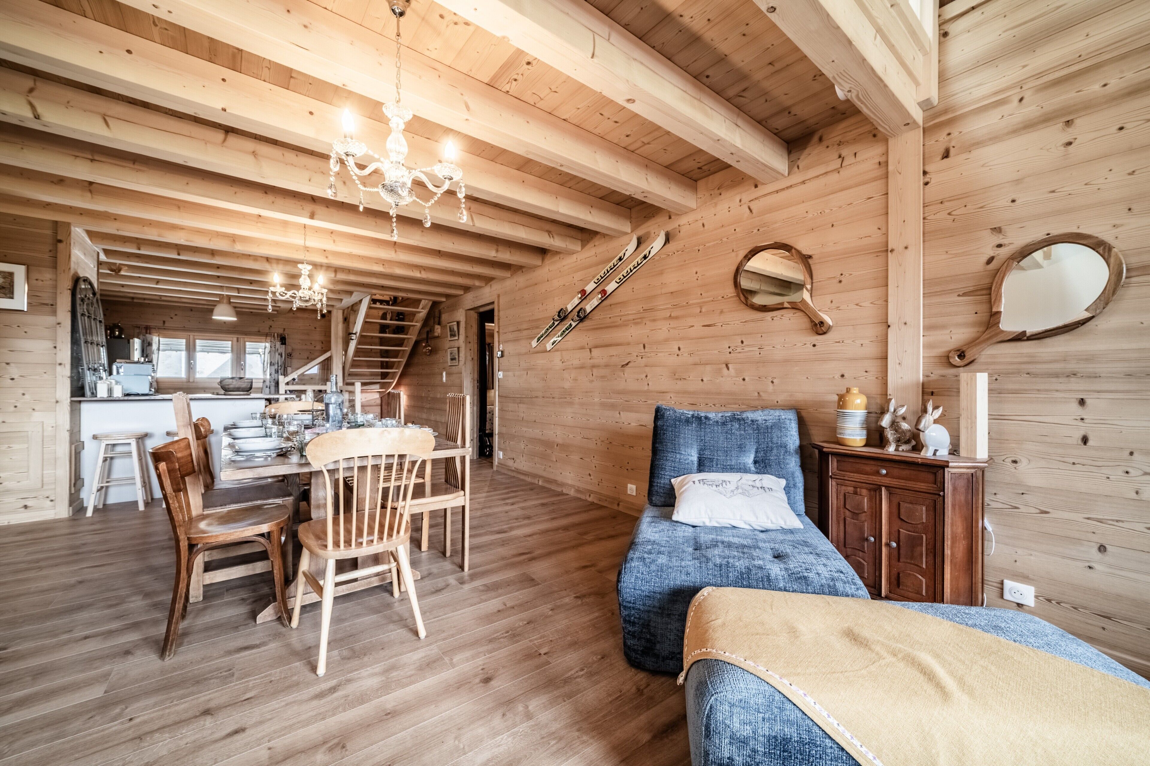 Un interior de madera con comedor, cama y escalera.