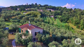 Una proprietà su una collina con un piccolo edificio, immersa nel verde e con cielo sereno.
