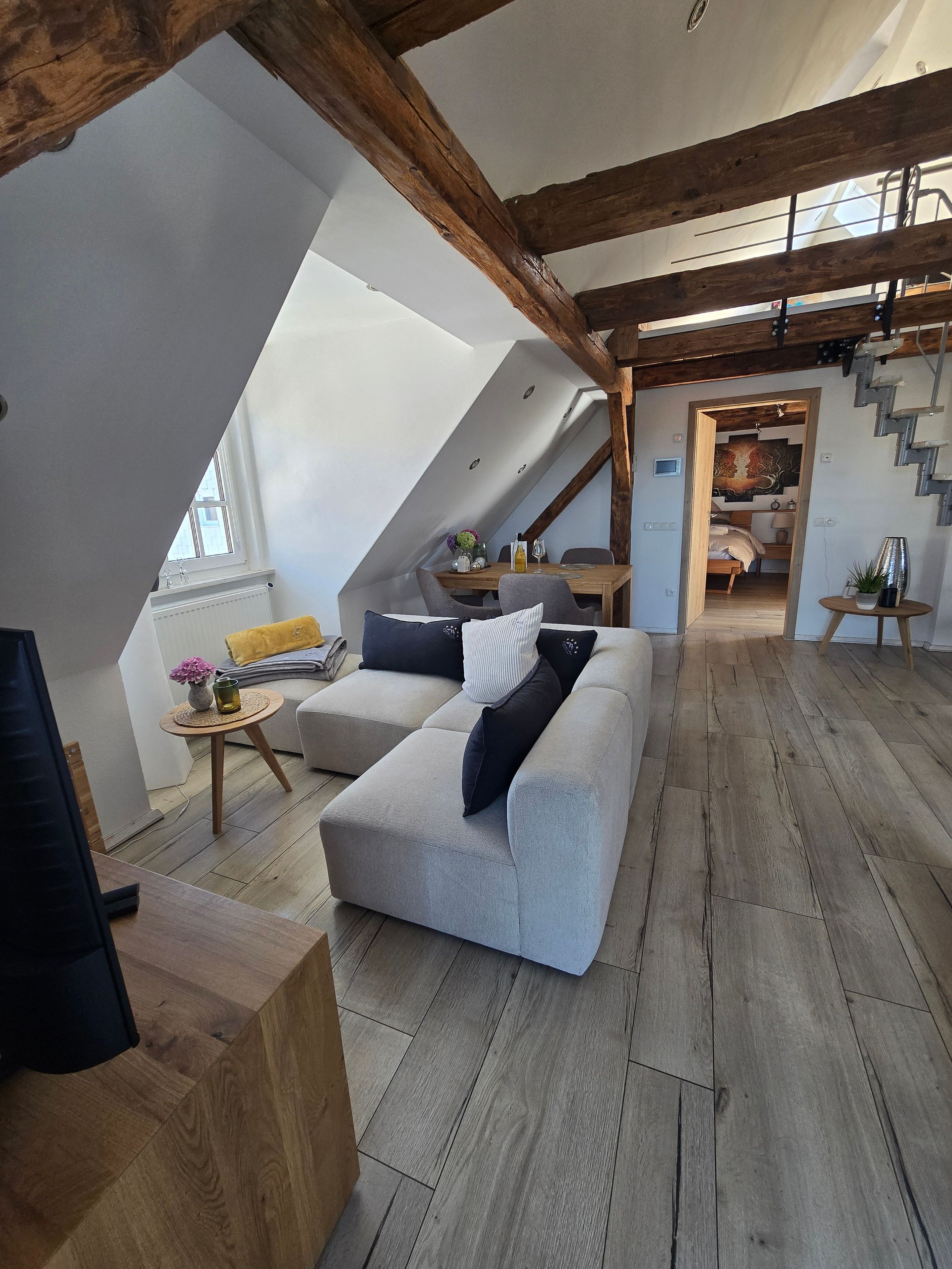 Un espace de vie de style loft avec un plafond en pente, un canapé, une table à manger et un escalier.