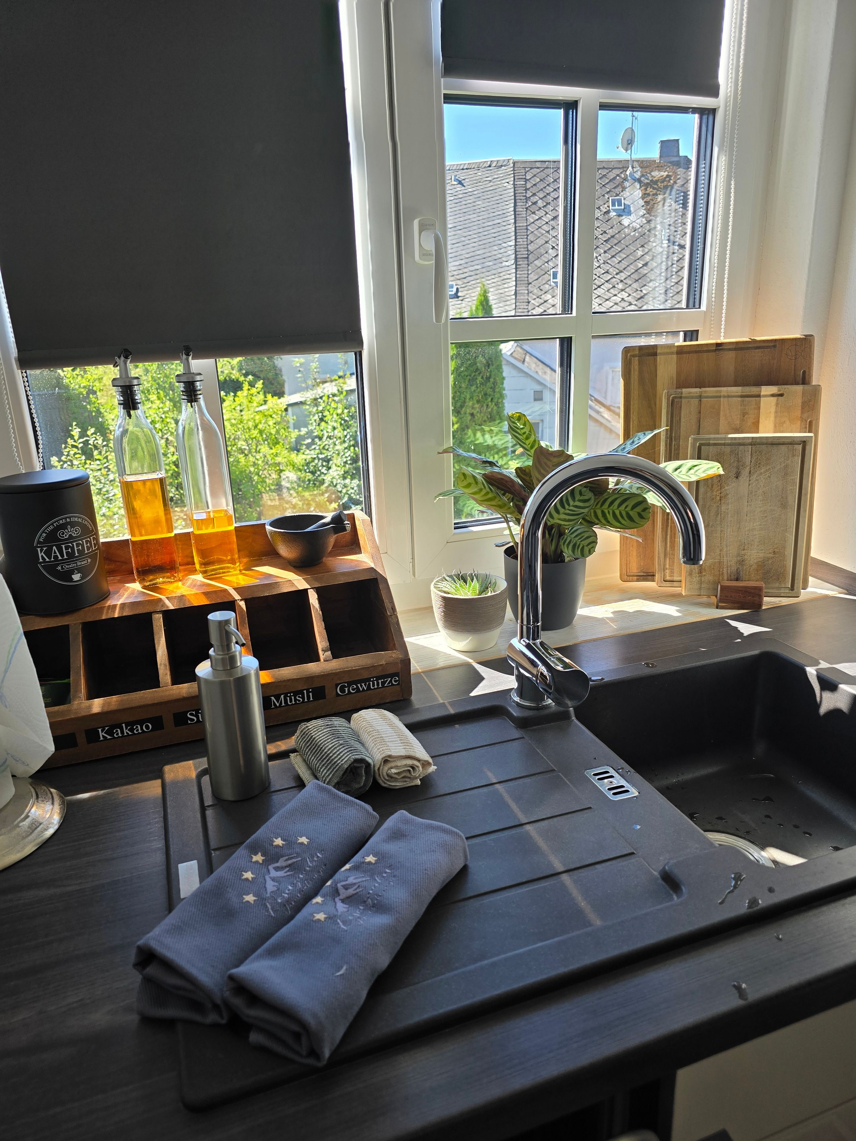 A kitchen with a window, a sink, a coffee machine, and a wooden storage unit.