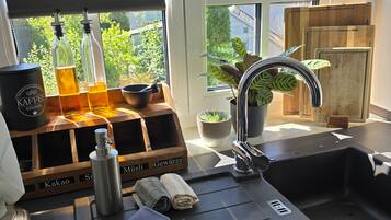 A kitchen with a window, a sink, a coffee machine, and a wooden storage unit.