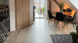 A modern kitchen with wooden beams, a dining area with a table and chairs, and a view through a glass door.