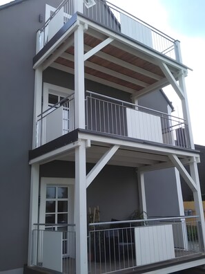 Un edificio de varios pisos con balcones, barandillas y una puerta.