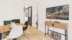 Ein zeitgemäßer Essbereich mit einem Holztisch, weißen Stühlen und einem Stadtbild an der Wand.