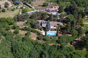 An aerial view of a residential area with houses, a swimming pool, and surrounding greenery.