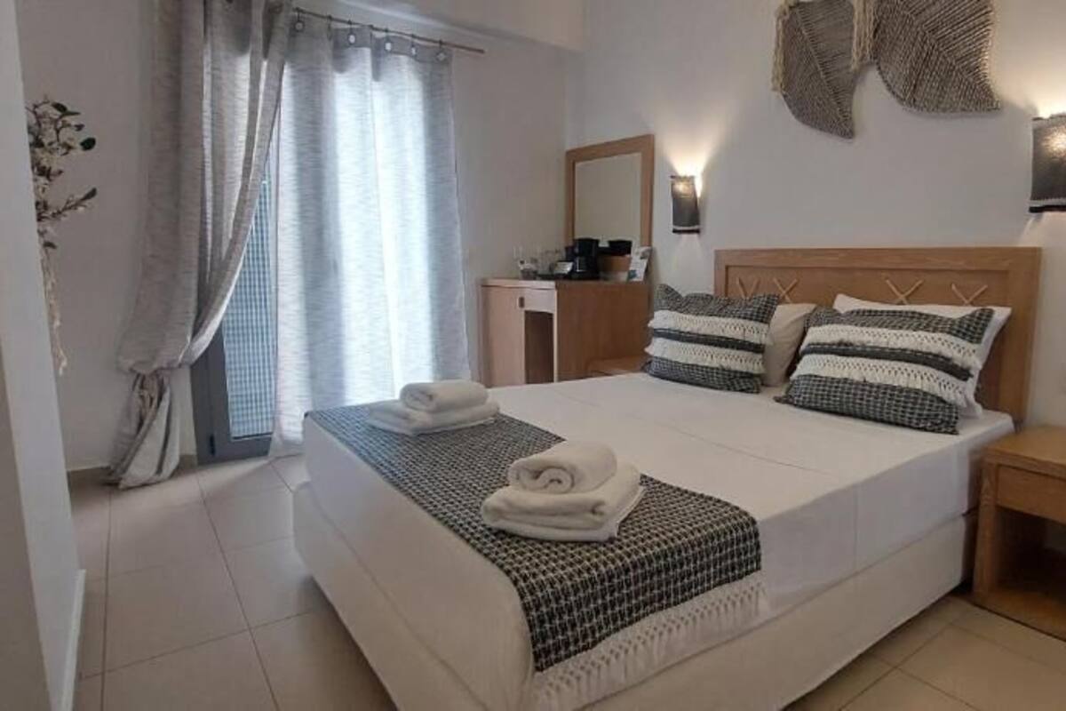 A neatly arranged bedroom with a large bed, bedside tables, a nightstand, a desk, and a mirror.