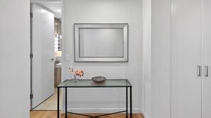 Un couloir avec une table dont le plateau est en verre, un bol et un vase rempli de fleurs.