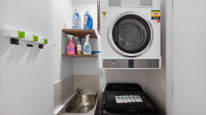 A compact laundry room with a washing machine, a dryer, and a sink. - 250SQM Cosy Bondi Escape Luxe 3BR & Parking (Bondi Beach)