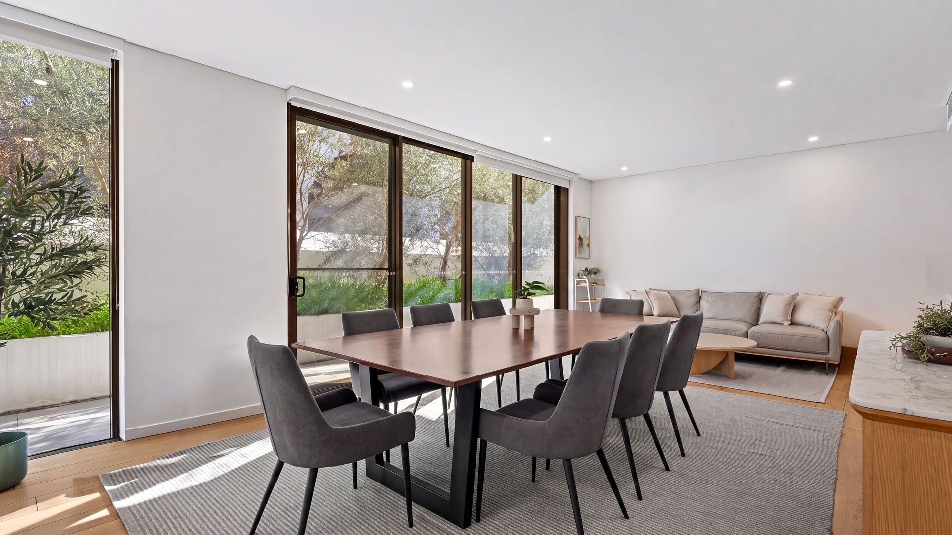 A modern conference room with a large table, six chairs, and a sofa.