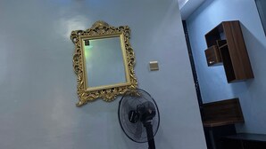 A room with a ceiling light fixture, a wall-mounted fan, a decorative mirror, and built-in wooden cabinets. - Simple And Classic With Affordable Family Bliss At DT-HOMES (ibadan)