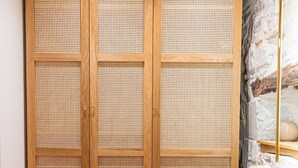 A bedroom with a wooden wardrobe, a stone wall, and a bed with a pink blanket. - Casa di Pietra Stone House (Kaštel Lukšić)