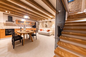 Une cuisine moderne avec des poutres en bois, un coin repas doté d’une table ronde et un mur en pierre en arrière-plan.