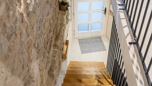 A wooden staircase with a stone wall on one side and a metal railing on the other. - Casa di Pietra Stone House (Kaštel Lukšić)