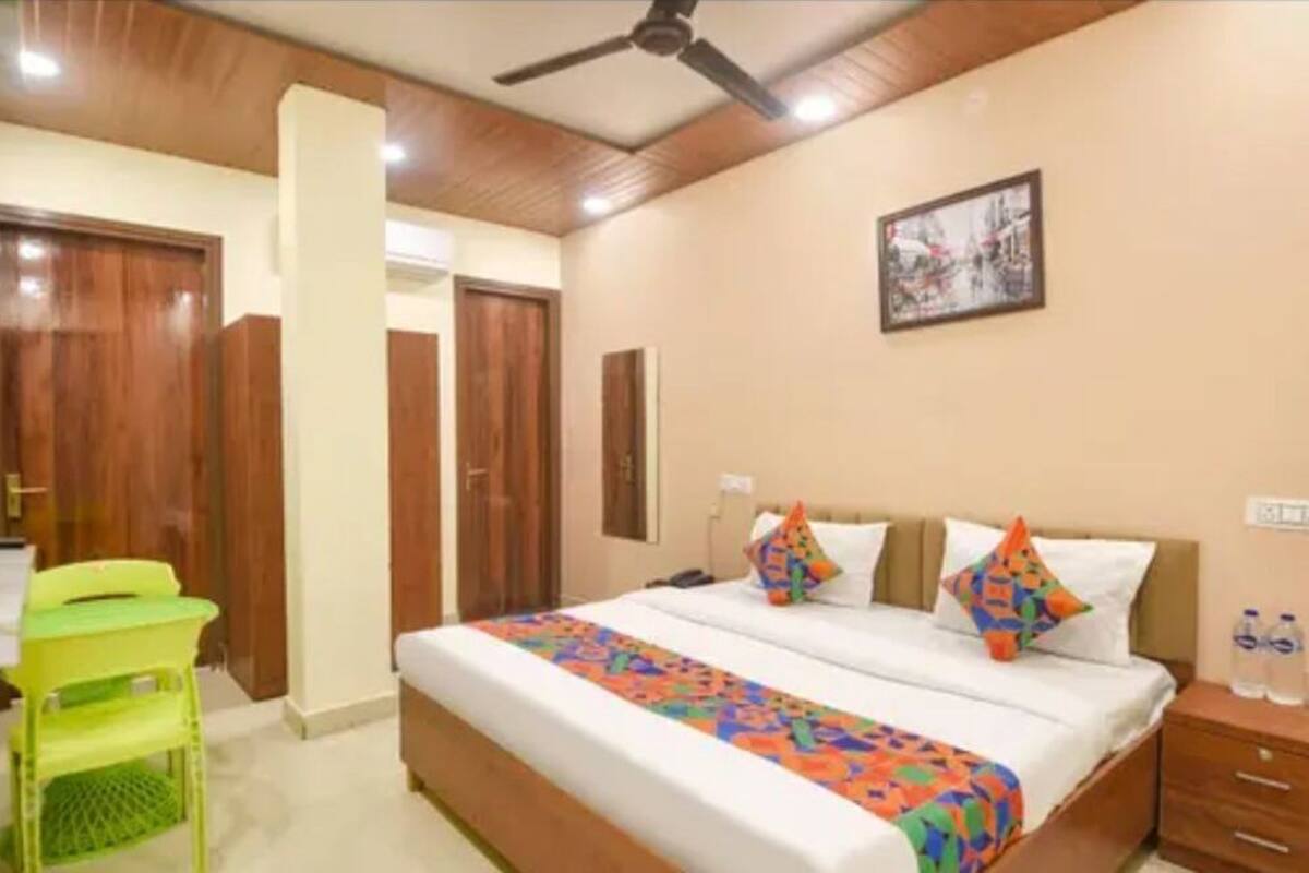 A hotel room with a bed, a desk, a chair, a wardrobe, and a ceiling fan.